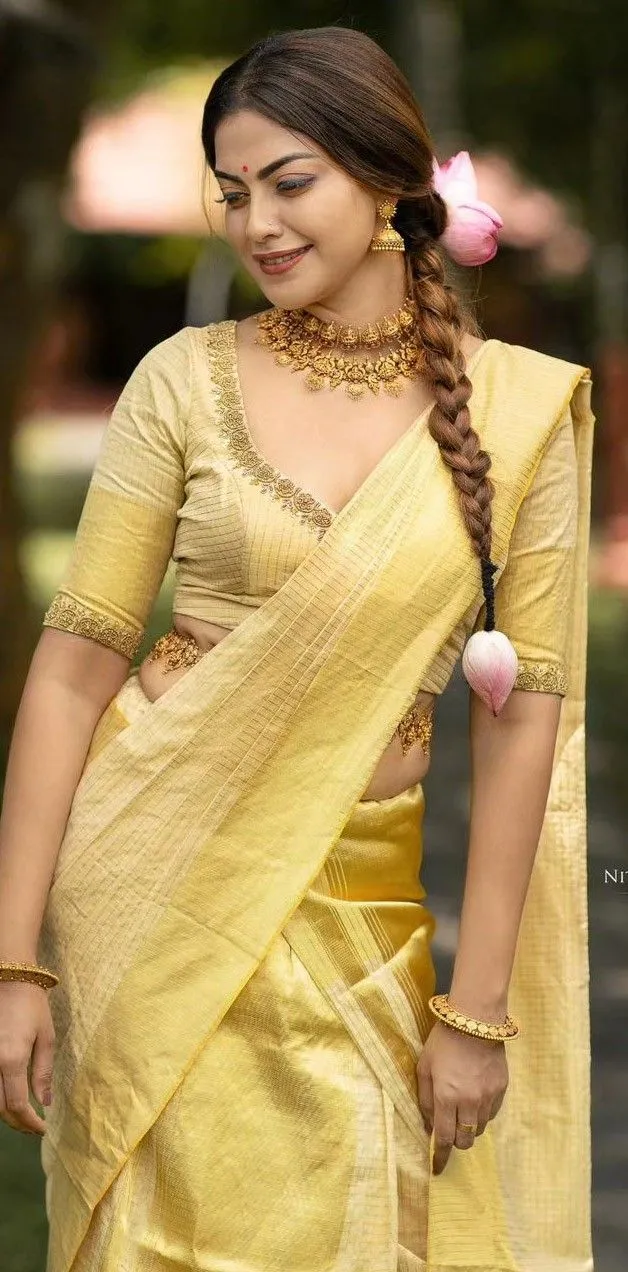 Anusree Nair in a golden saree with pink flower in her hair