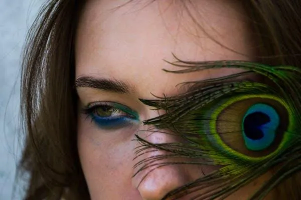 Artistic Photo of Woman with a Peacock Feather Near Her Face