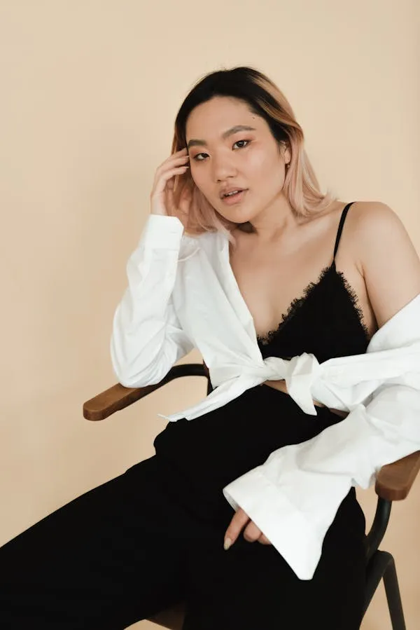 Asian Cute Woman Seated in a Chic Outfit Looking Thoughtful