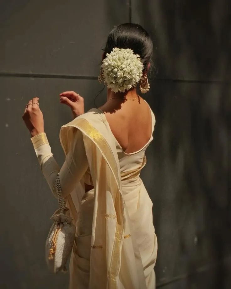 Back view of a woman in a golden Kerala saree with a bag