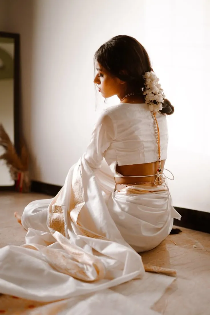 Back view of a woman in a Kasavu saree with a flower on head