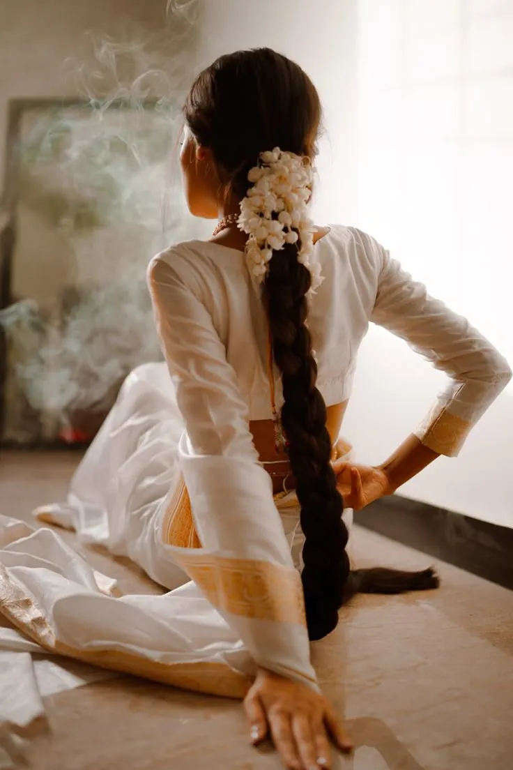 Back view of a woman in a Nerial saree sitting on the floor