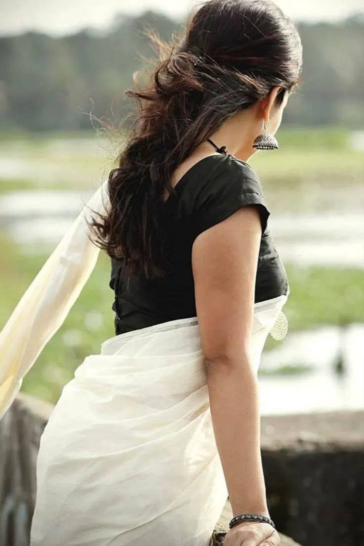 Back view of a woman wearing a white saree with black blouse