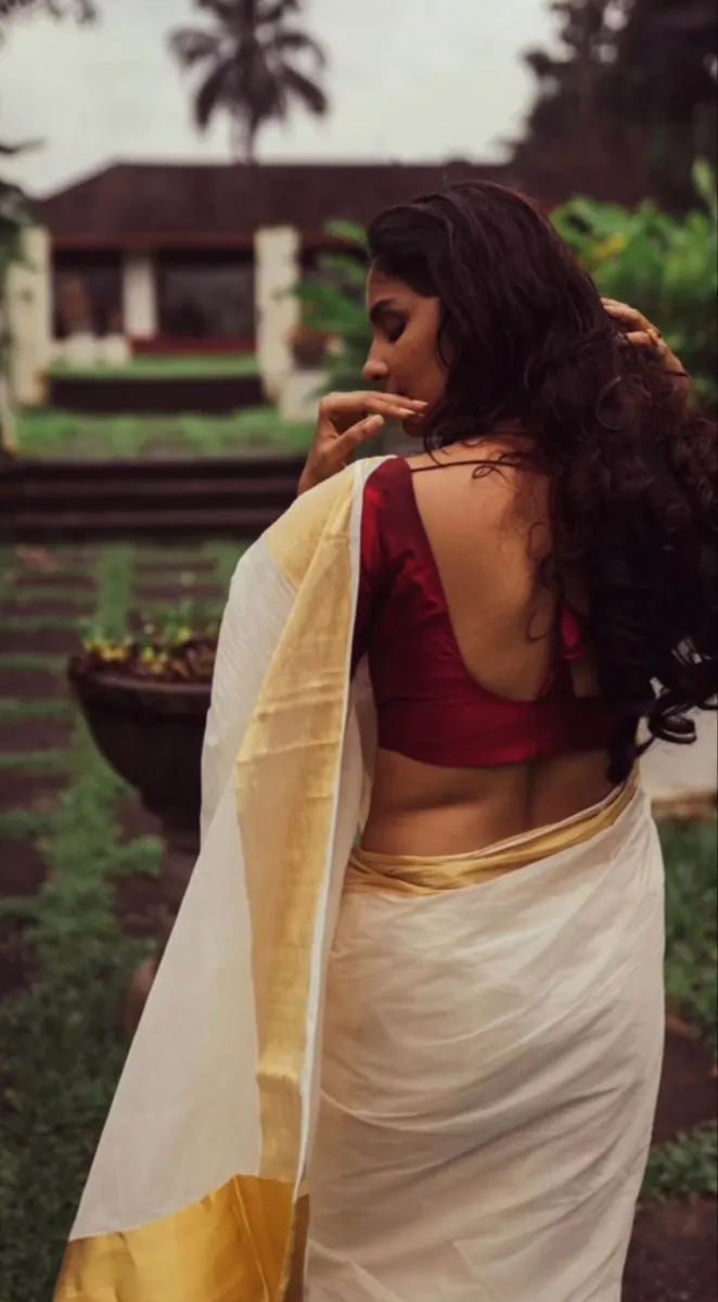 Back view of a woman wearing white saree with golden border