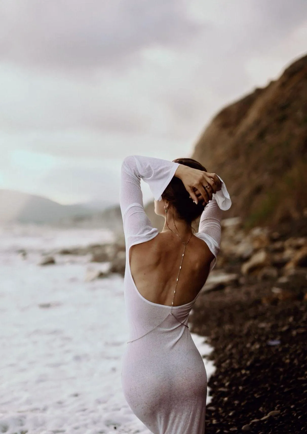 Back View of a Woman in a White Dress Posing Near the Ocean