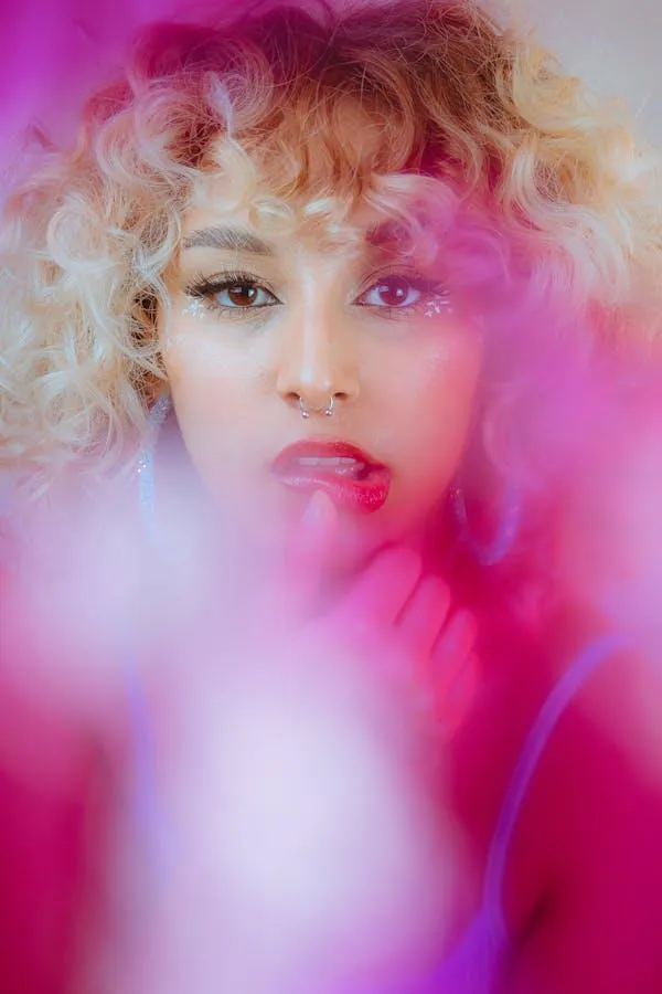 Blonde Model with Curls Posing Behind Soft Pink Light Image