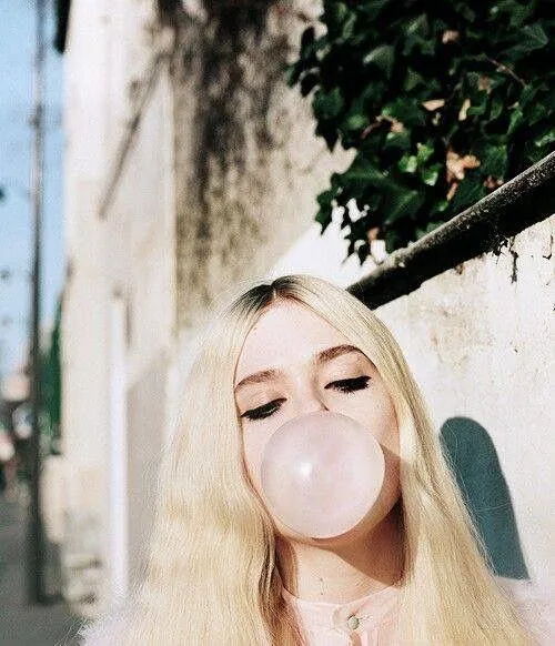 Blonde Woman Blowing Bubble Gum Outdoors in the Sunlight
