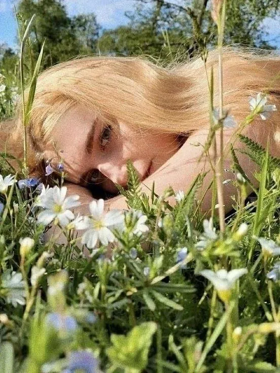 Blonde Woman Lying in a Field of Wildflowers on the Grass