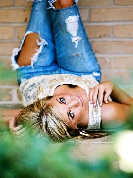 Blonde Woman Lying on the Ground Wearing Ripped Jeans Image