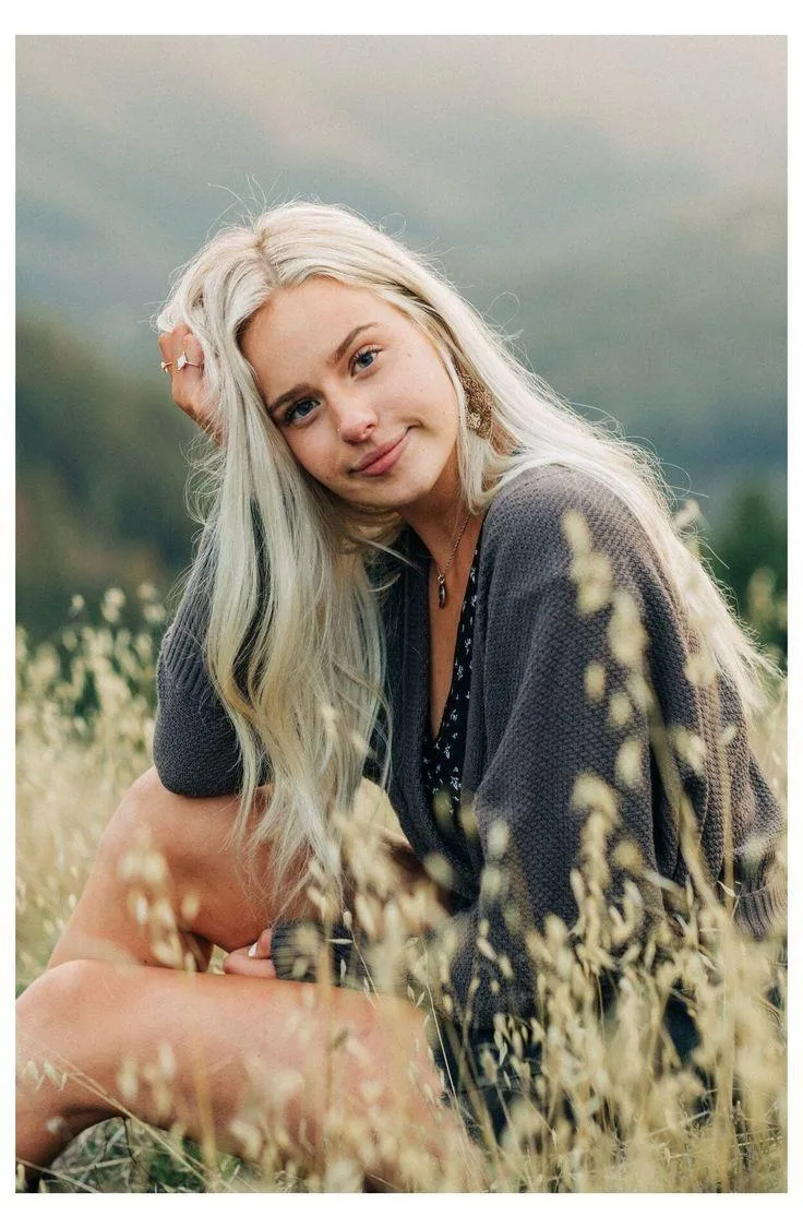 Blonde Woman Sitting in Tall Grass with a Soft Smile Image