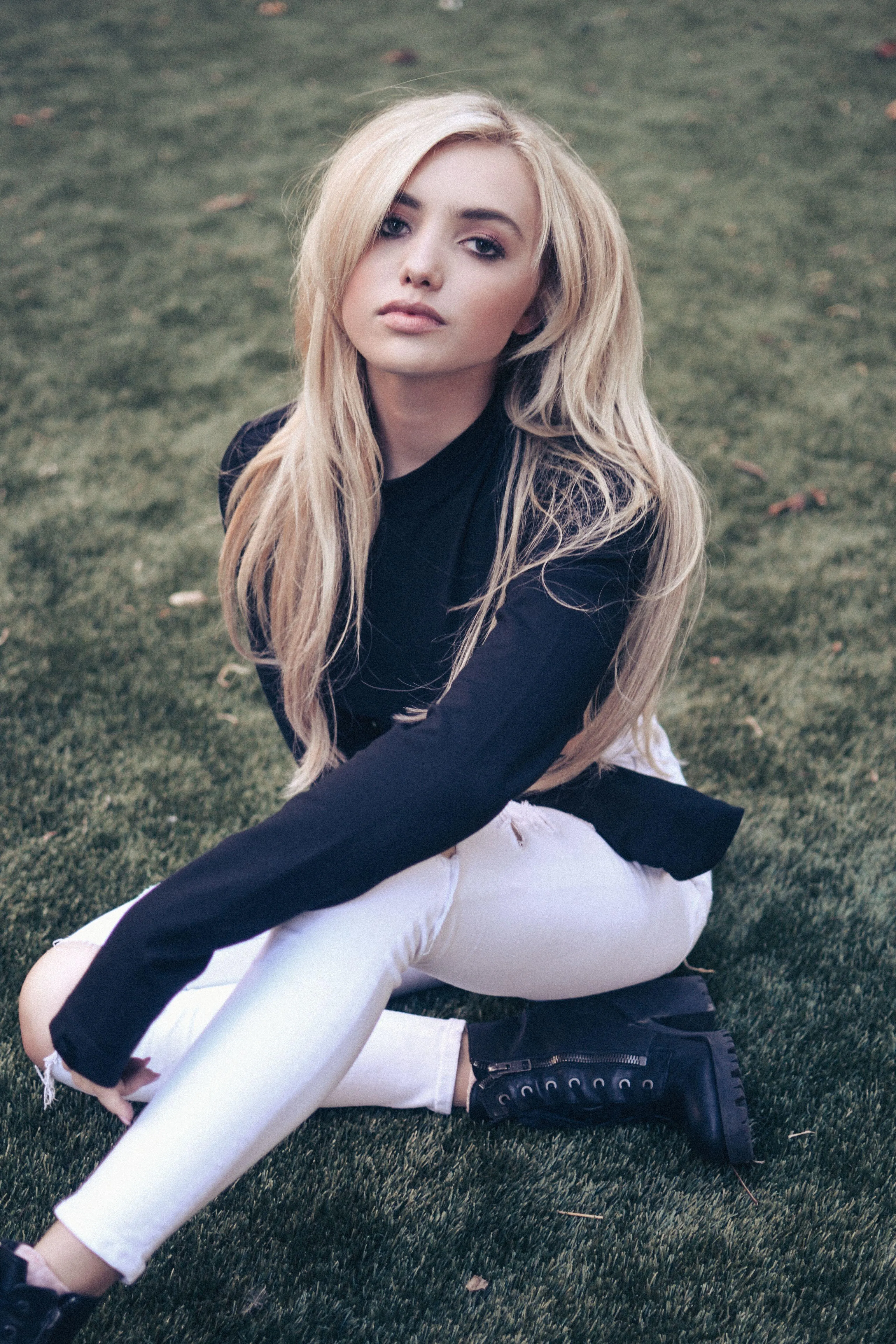Blonde Woman Sitting on the Grass in a Casual Outfit Image