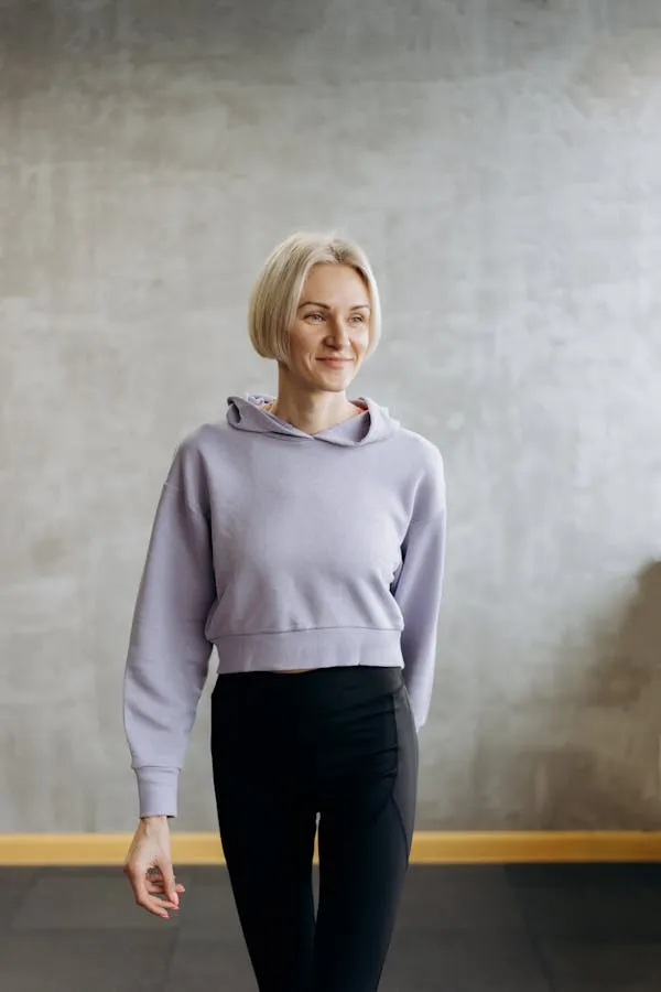 Blonde Woman Standing in a Casual Outfit Against a Gray Wall
