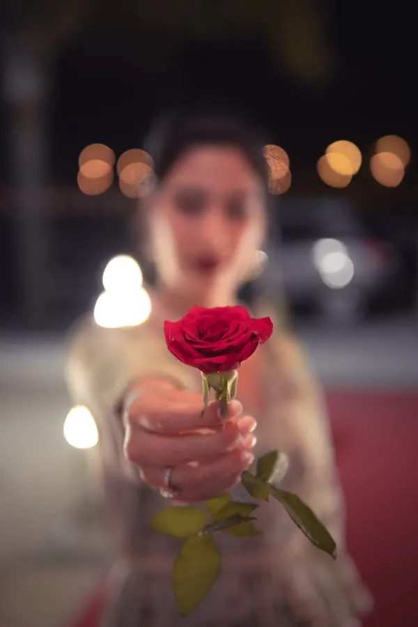 Blurry Image of a Woman Holding a Red Rose Free Wallpaper