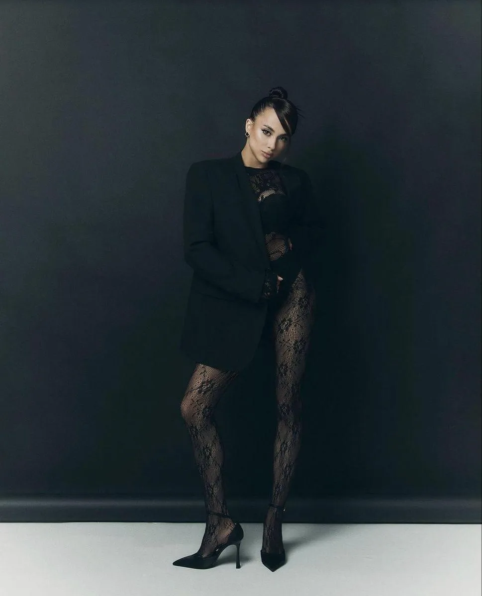 Bold Woman in a Dark Outfit Posing Confidently in a Studio