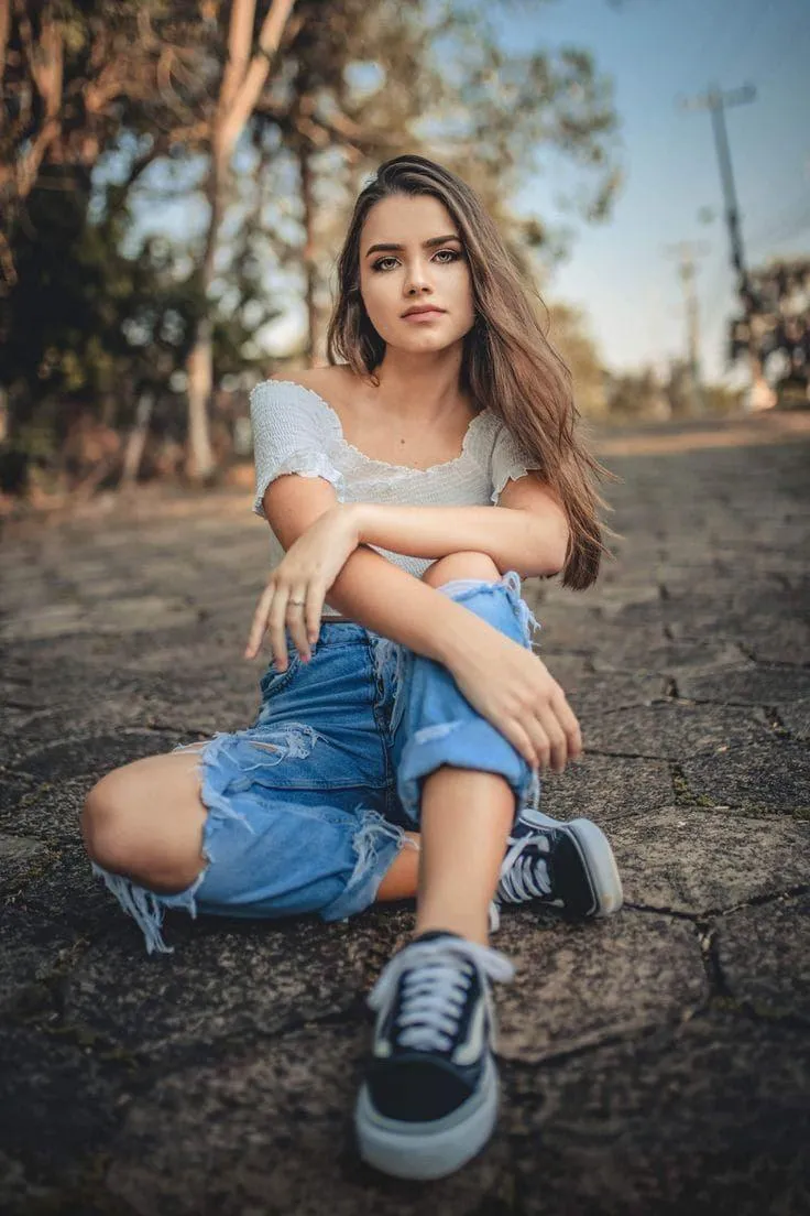 Casual Girl Sitting on the Pavement in Denim and Sneakers
