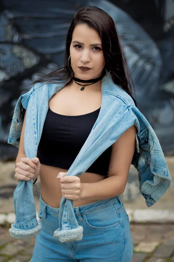 Casual Young Woman in Denim Outfit Posing Near a Stone Wall