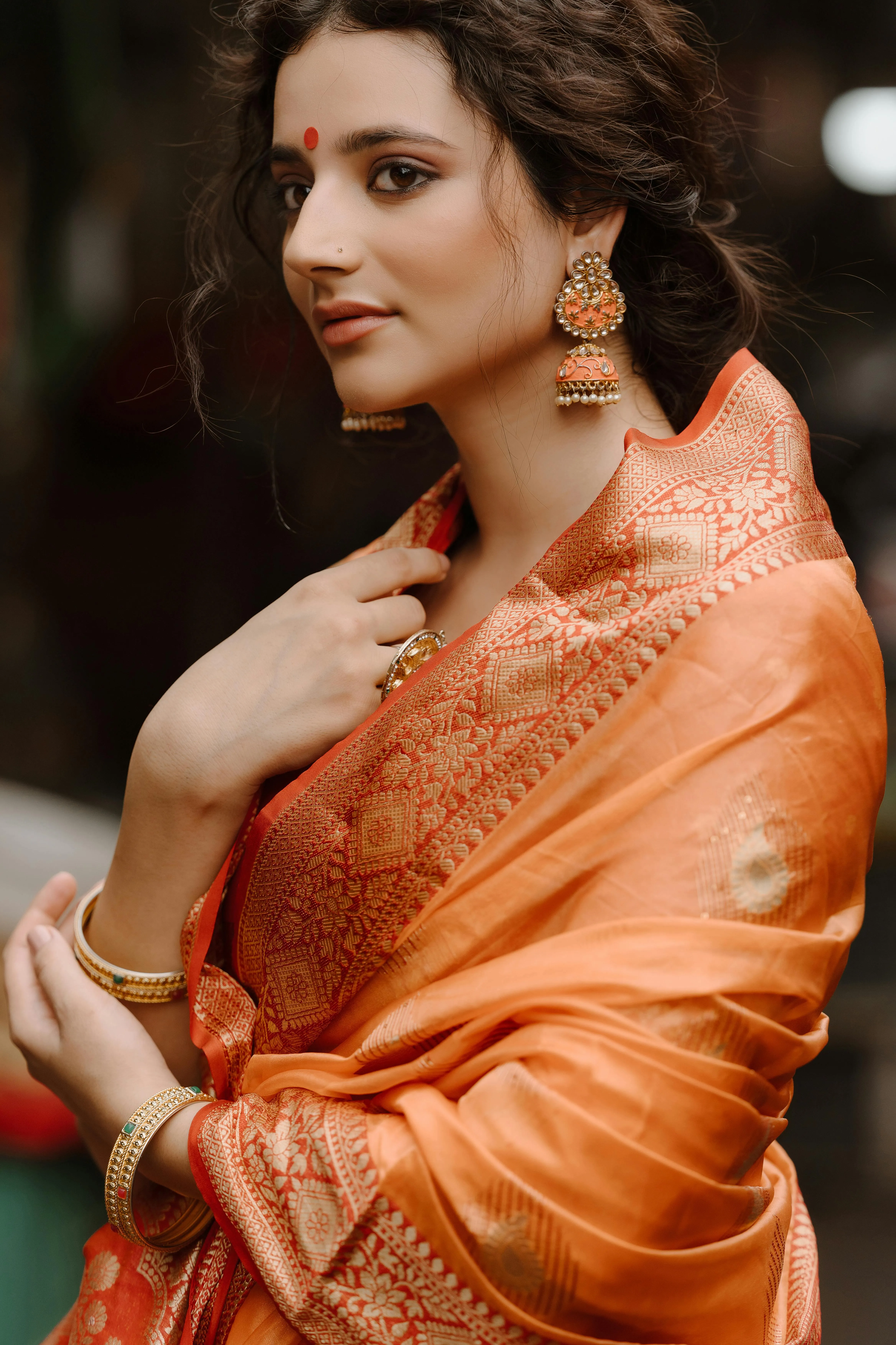 Charming Young Woman in Orange Saree Side Glance Pose Image