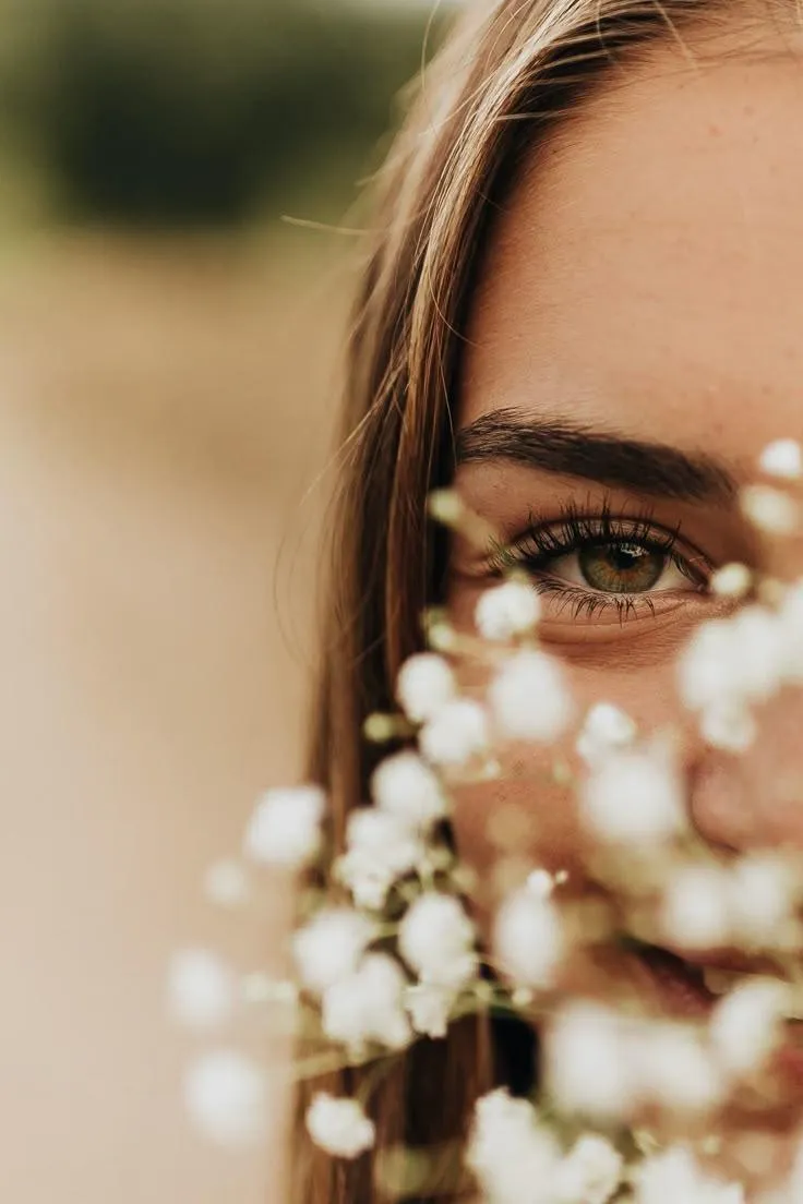Close Up of a Cute Woman Behind White Flowers in Soft Light