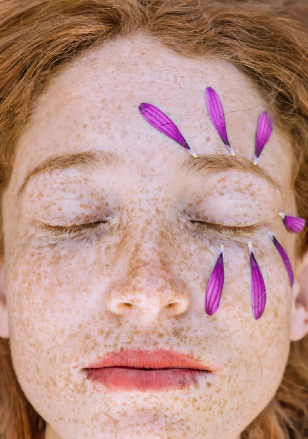 Close Up of a Woman with Freckles and Purple Flower Petals