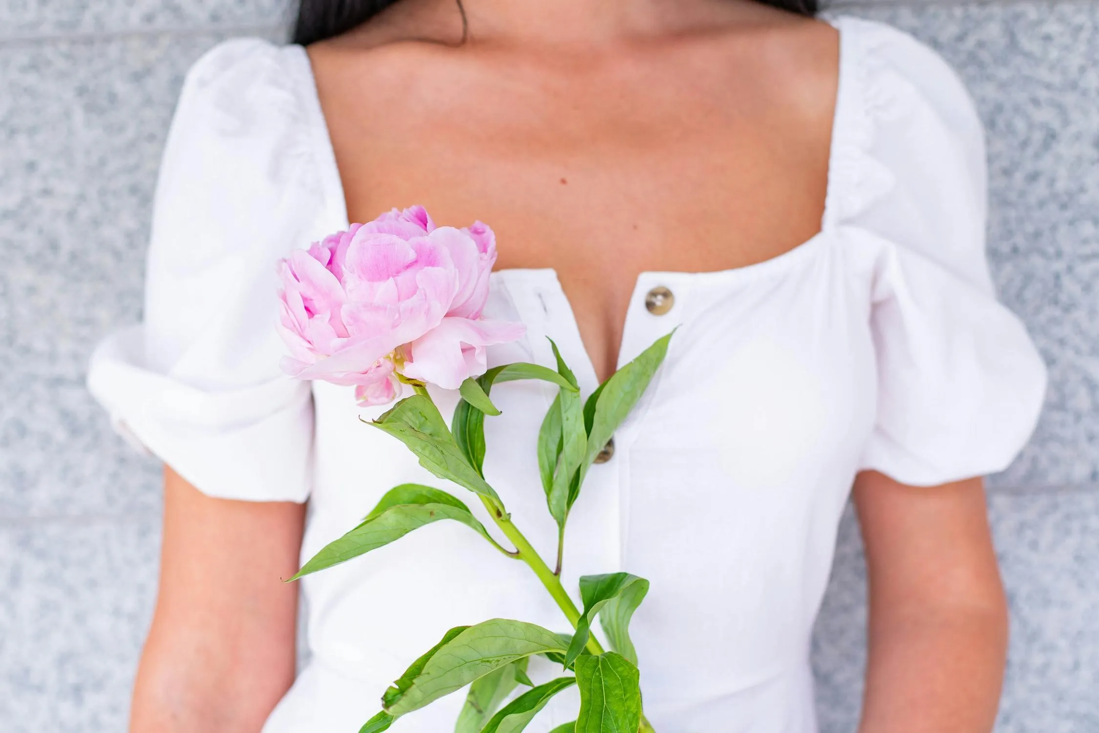 Close Up of a Woman Holding Pink Flowers with a White Dress