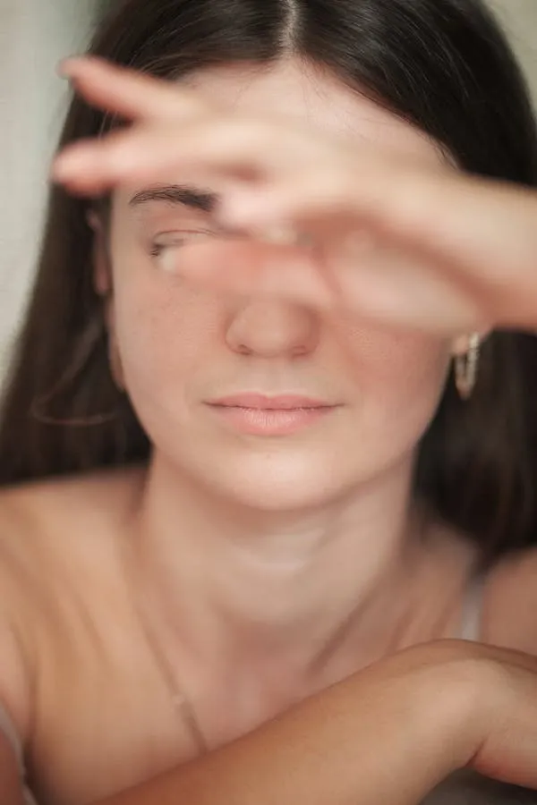 Close Up of a Woman Shielding Eyes From Light with Her Hand