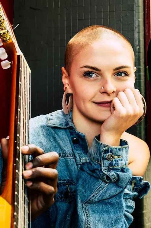 Confident Bald Woman Smiling and Leaning on Colorful Guitar