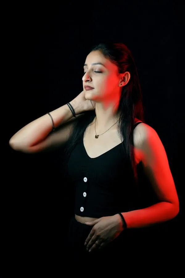 Confident Woman in Black Dress Posing in Red Light Wallpaper