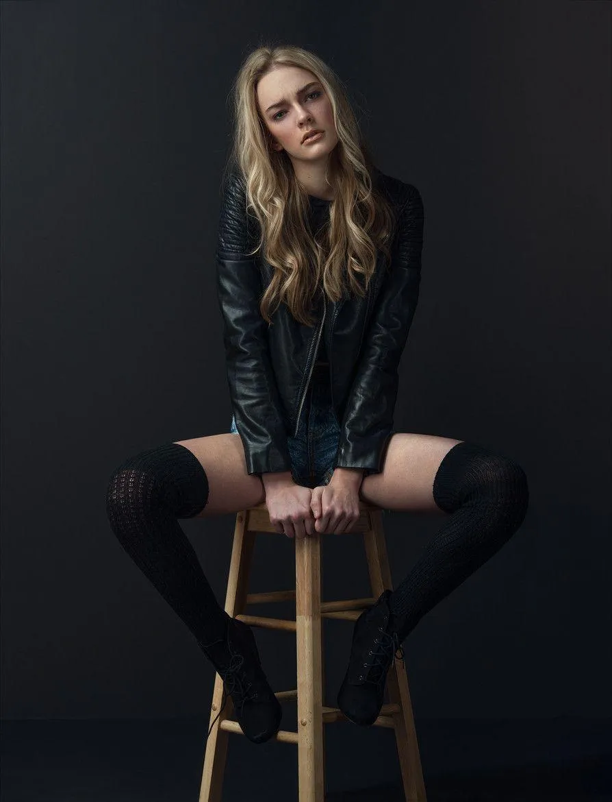 Confident Woman in a Black Sitting on a Wooden Stool Image
