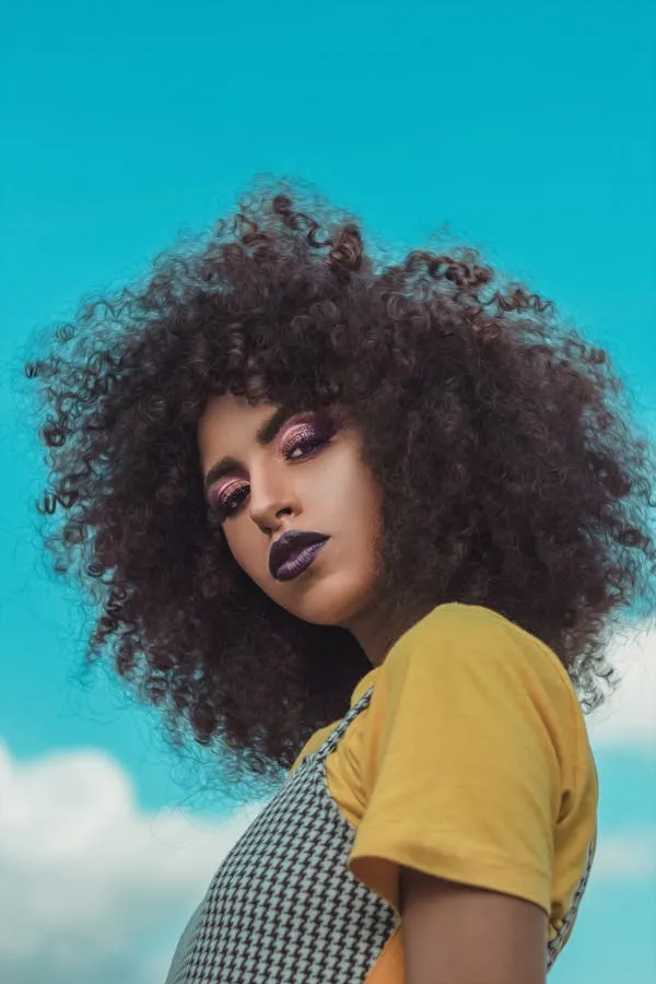 Confident Woman with Curly Hair in Yellow Top Free Wallpaper