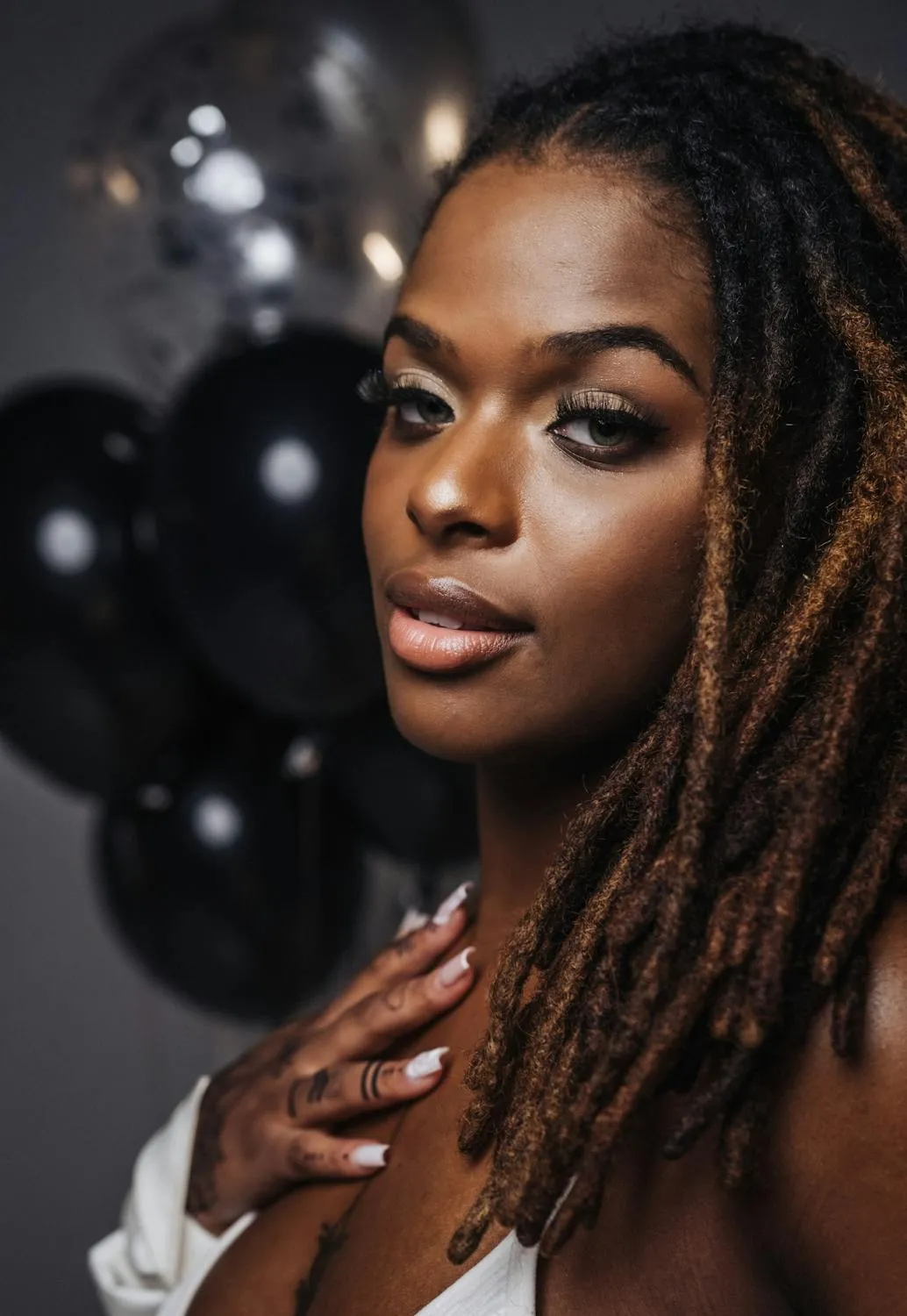 Confident Woman Posing with Dreadlocks and Black Balloons