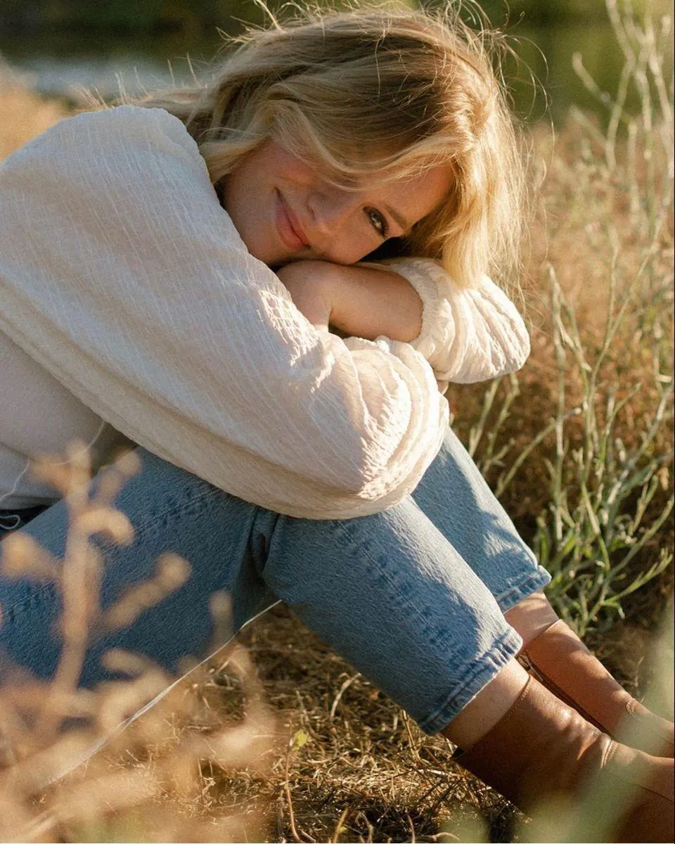 Cozy Woman in Sweater Resting on Grass During a Fall Day