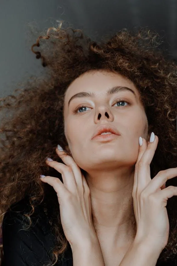 Curly Haired Woman Posing with Her Hands Near Her Face
