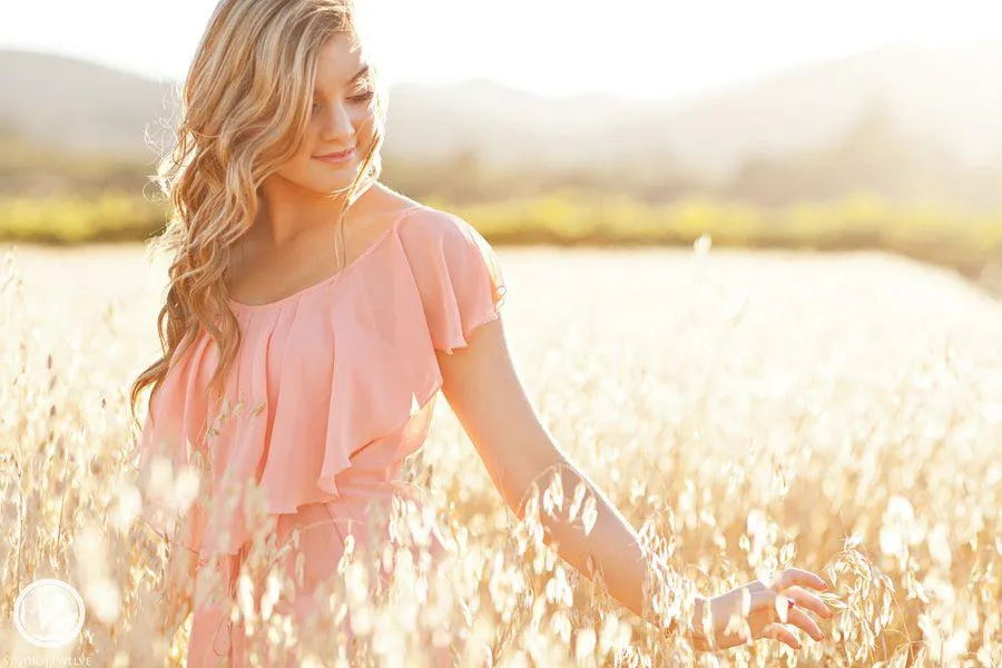 Cute Woman in a Pink Dress Walking Through a Sunlit Field