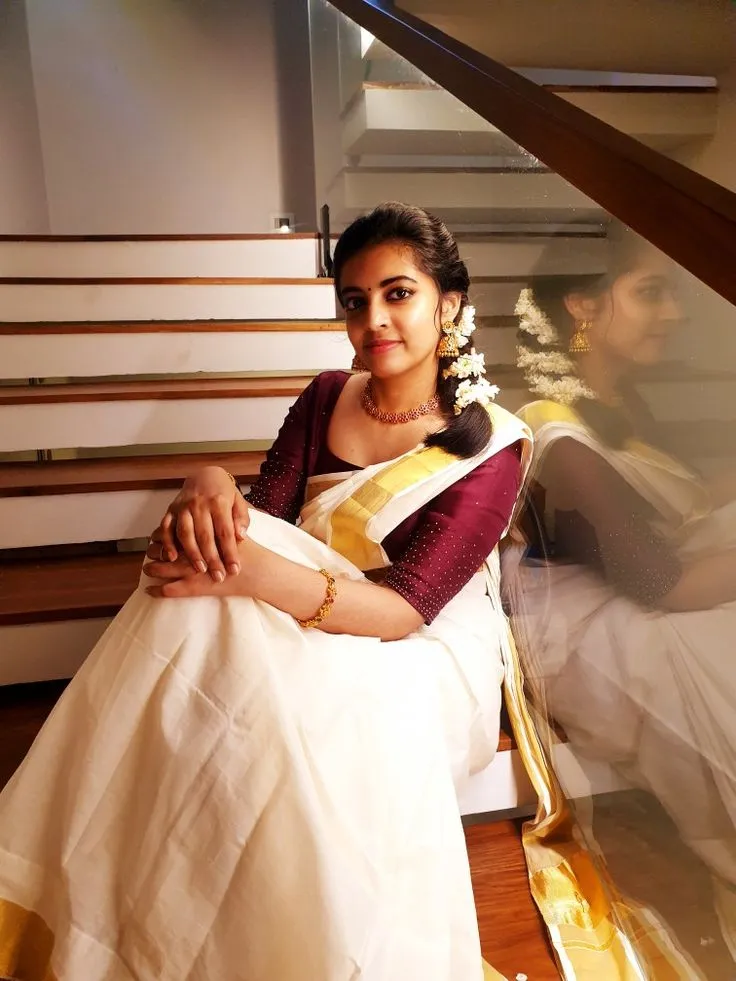 Cute woman sitting on the steps wearing a kasavu saree image