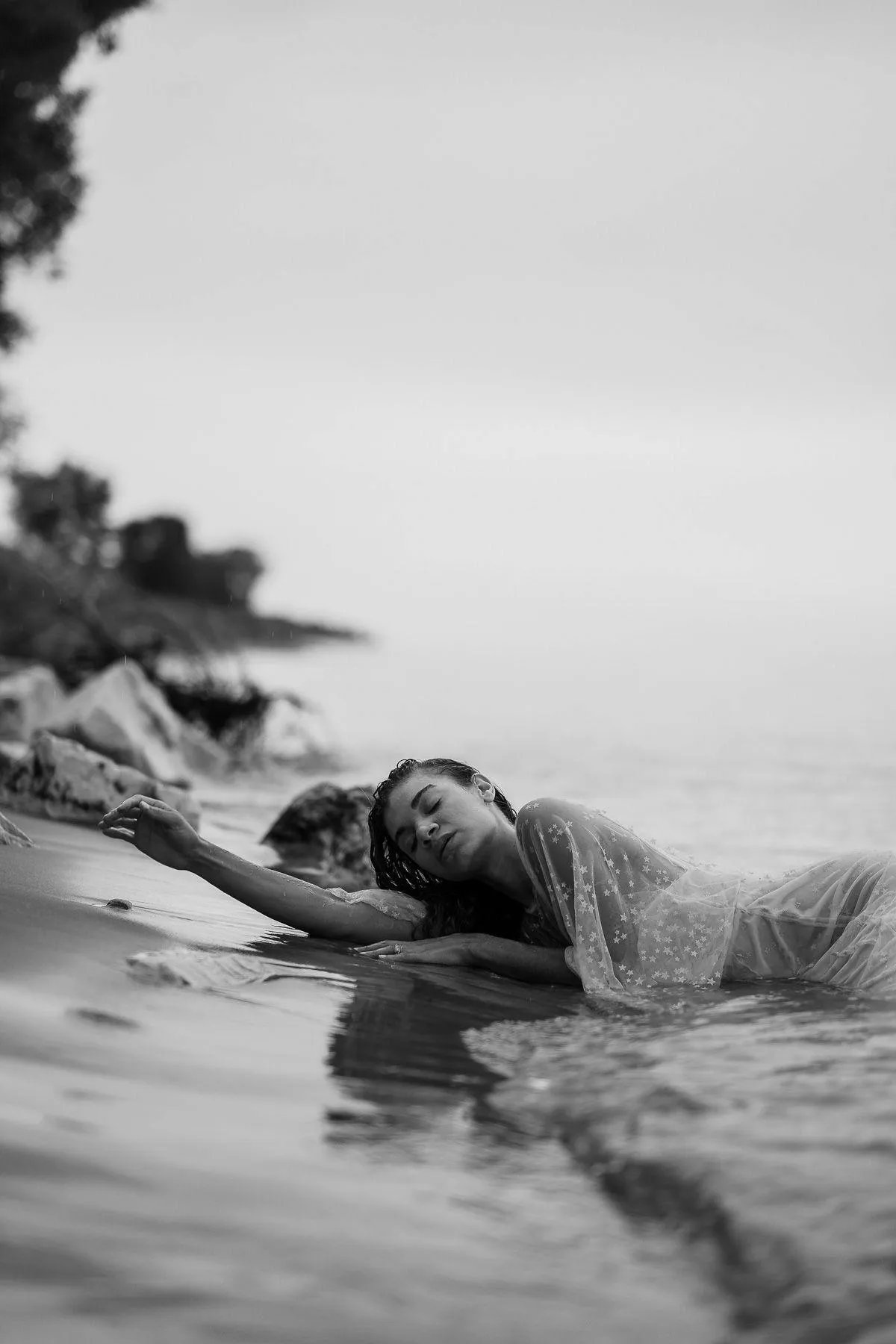 Dreamy Black and White Photo of a Woman Lying by the Shore