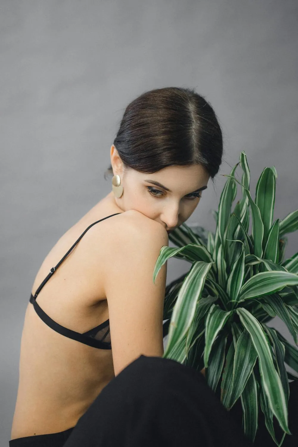Elegant Woman in a Black Dress Sitting Next To a Green Plant