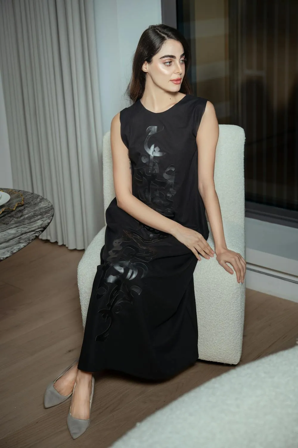 Elegant Woman in a Black Dress Sitting on the Sofa Wallpaper