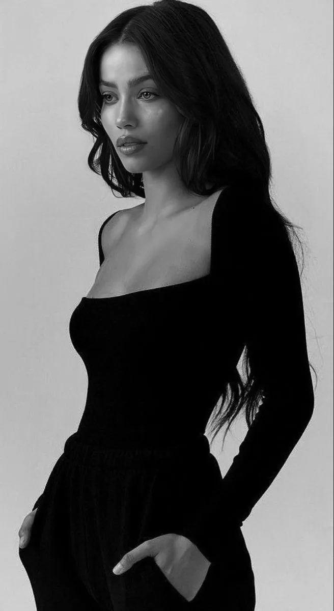 Elegant Woman in Black Dress Standing Against a White Wall