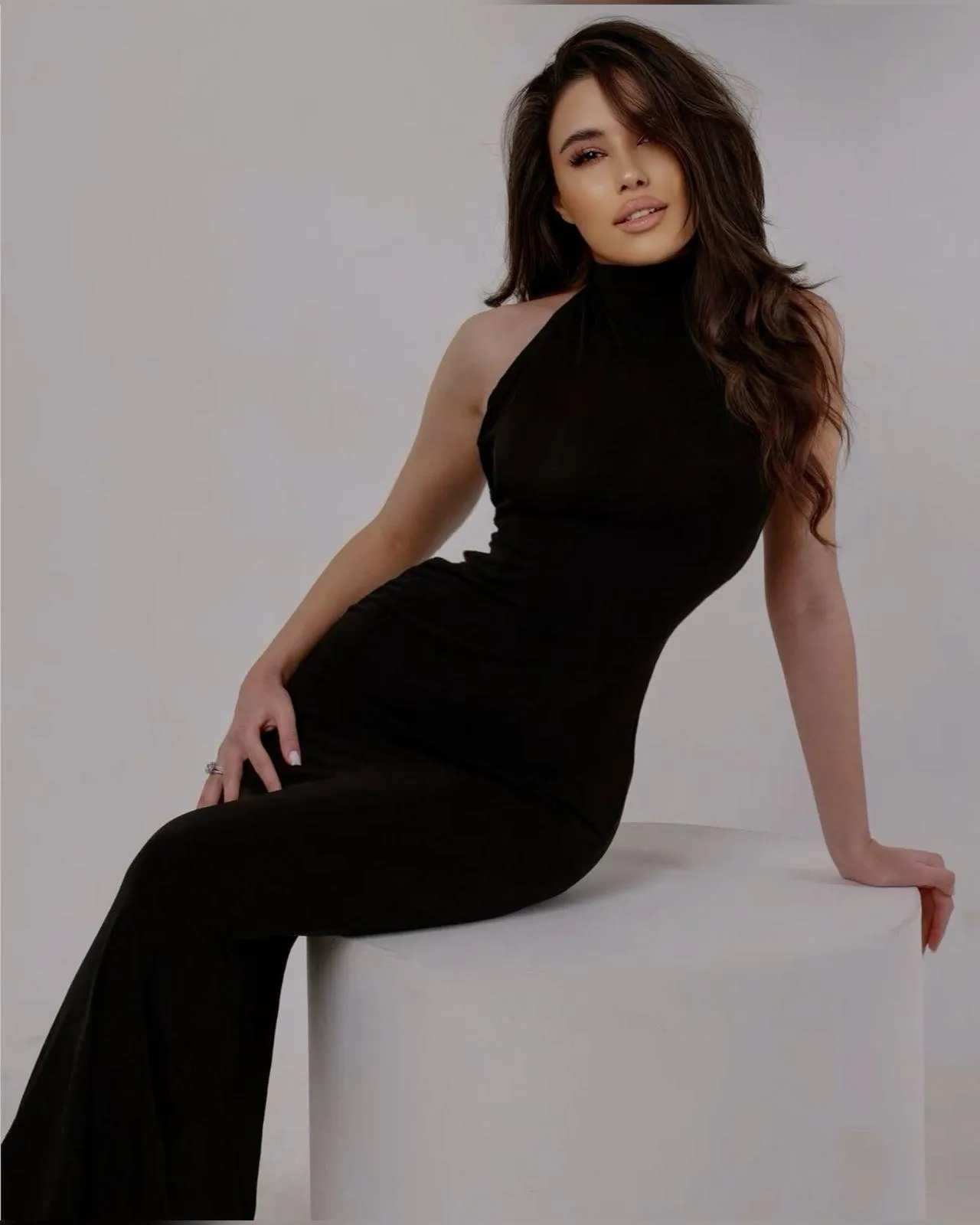 Elegant Woman with a Black Gown Seated on a White Platform