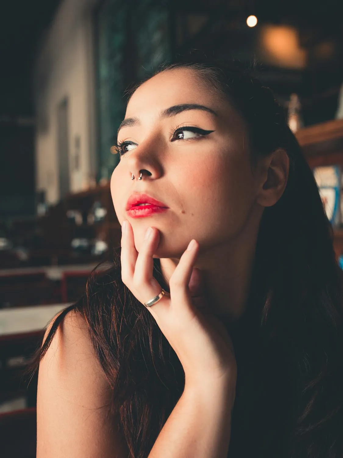 Elegant Woman Gazing Sideways in Low Light Restaurant Image