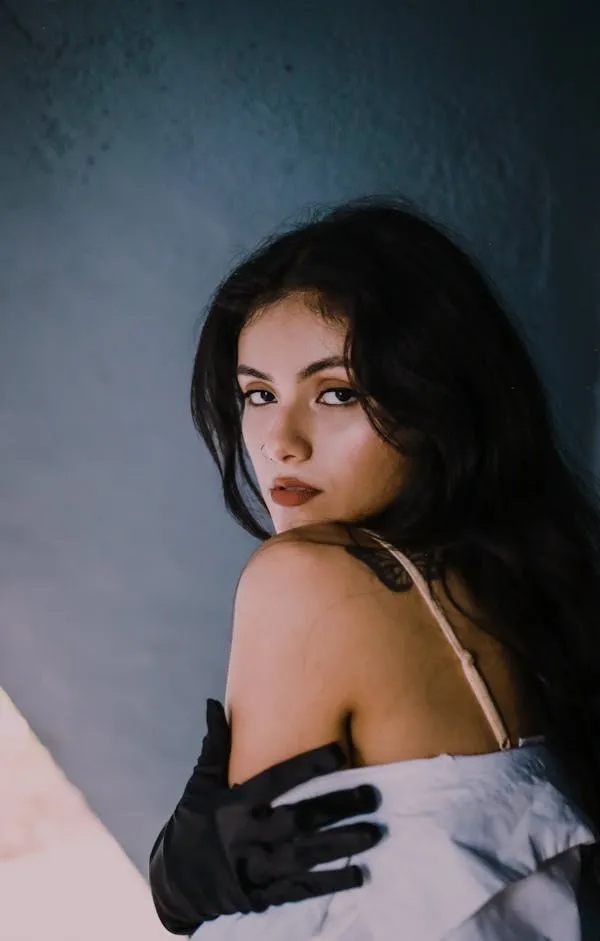 Elegant Woman in Gloves Looking Back in Soft Lighting Image