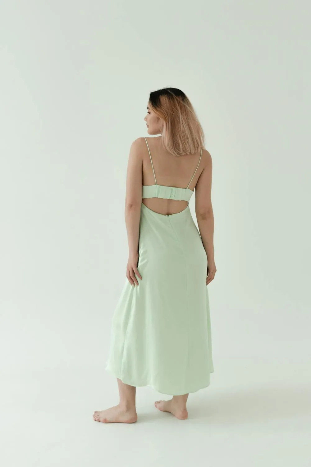 Elegant Woman in Light Green Dress Standing with Back Turned