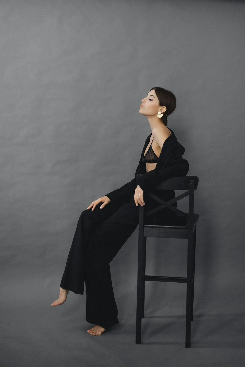 Elegant Woman Sitting on a Chair Against a Gray Background