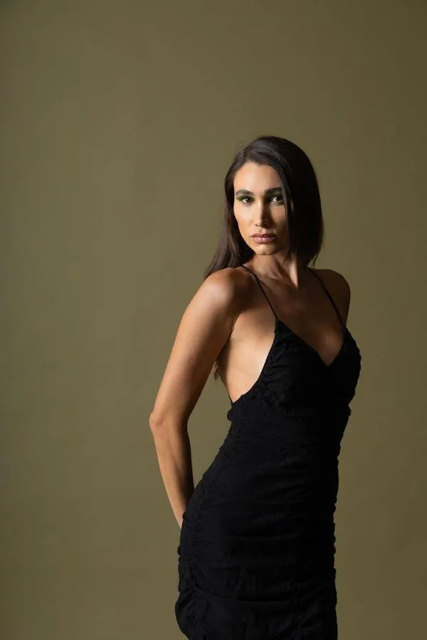 Elegant Woman Wearing a Black Dress Poses in a Simple Studio