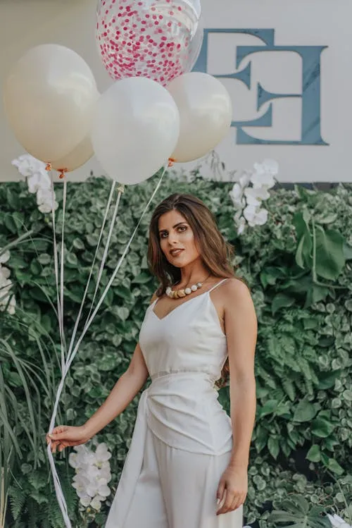 Elegant Woman in White Dress Stands with Balloons and Decor