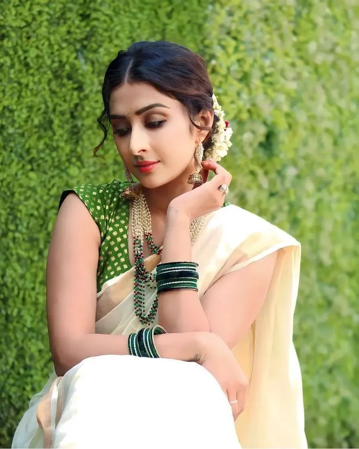 Farnaz Shetty in a kasavu saree near a green background