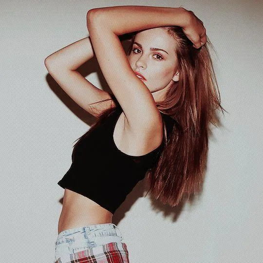 Fashionable Girl Posing with Arm Up in Front of a White Wall