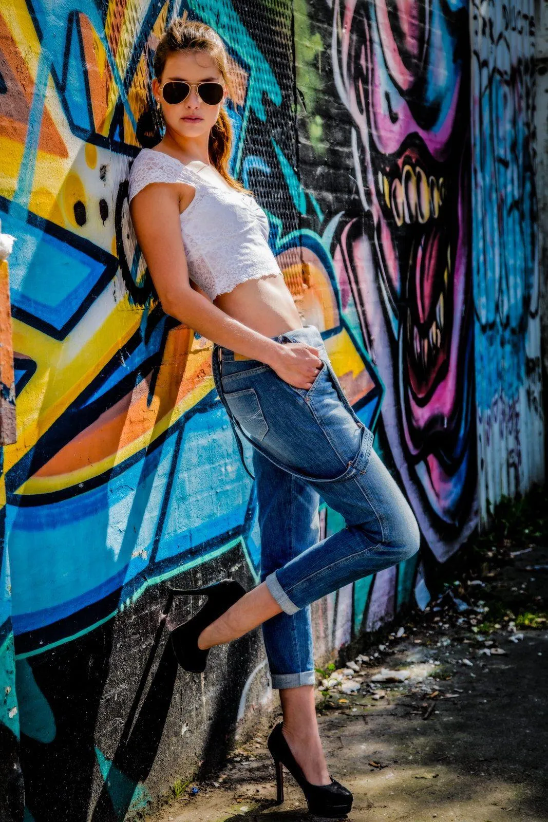 Fashionable Woman Posing in Front of Colorful Graffiti Wall