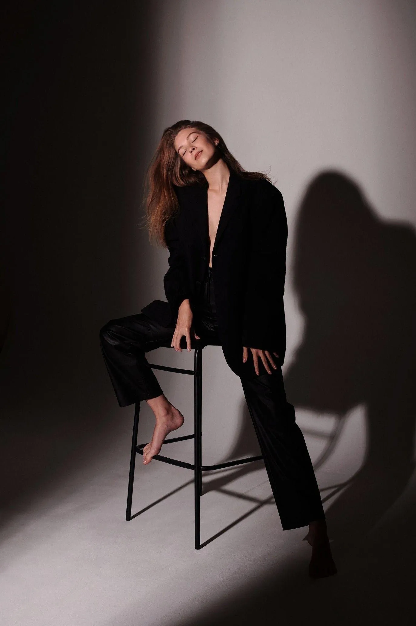 Fashionable Woman in a Suit Sitting Confidently on a Stool