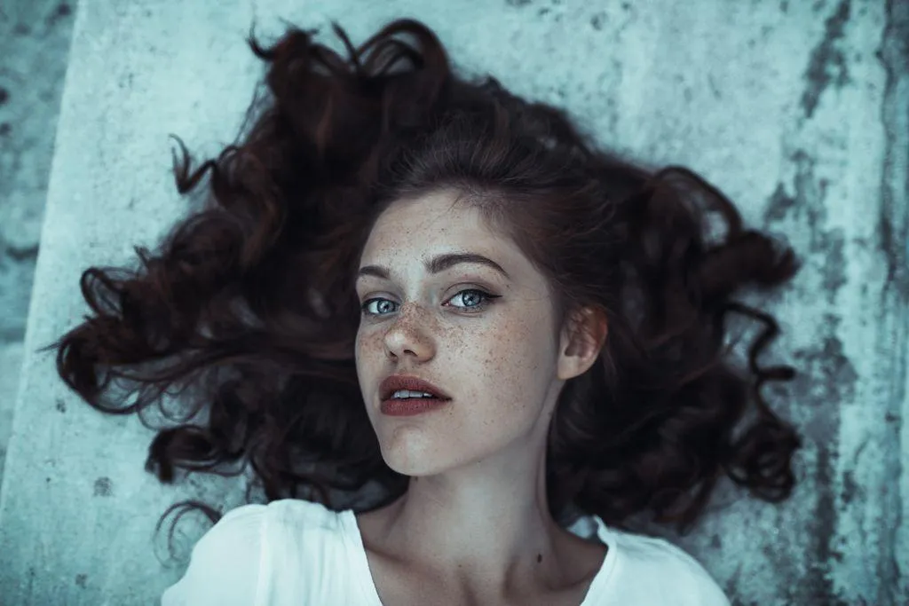 Female Model with Curly Hair Lying on the Ground Looking Up